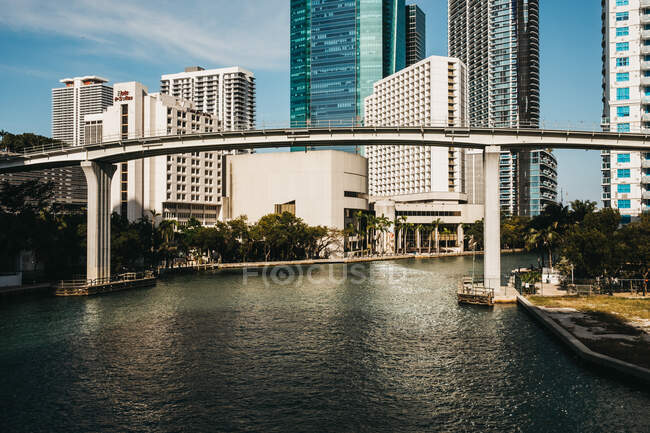 Vista del río tranquilo que fluye bajo el puente moderno a través de la magnífica ciudad de Miami - foto de stock