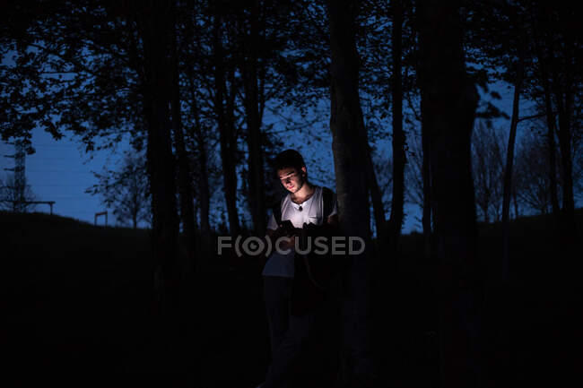 Homem usando smartphone na floresta escura — Fotografia de Stock