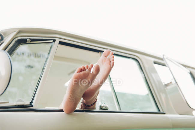 Close-up of female legs in car window — Stock Photo
