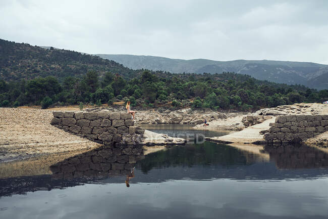 Giovane donna seduta sulla roccia vicino all'acqua — Foto stock
