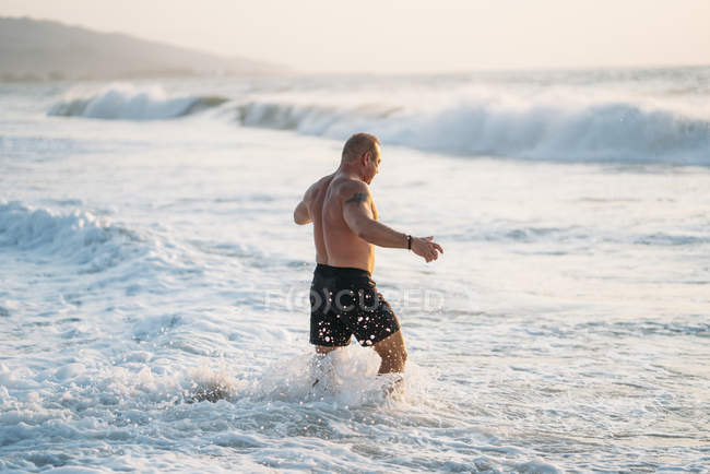 Forte vecchio fa esercizio sulla spiaggia — Foto stock