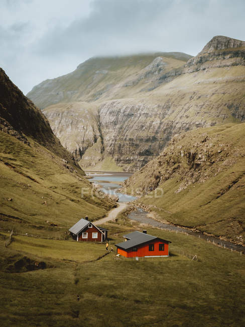 Rote Häuser am Gebirgsfluss am Hang auf Feroe-Inseln — Stockfoto