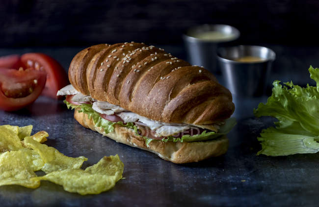 Big sandwich with vegetables and chicken on grey table — Stock Photo