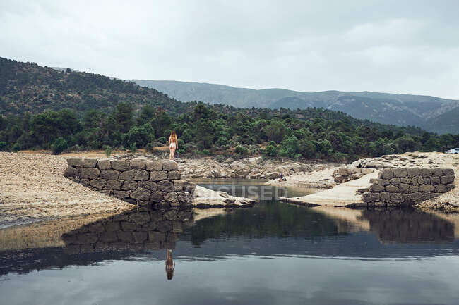 Junge Frau steht auf Felsen am Wasser — Stockfoto