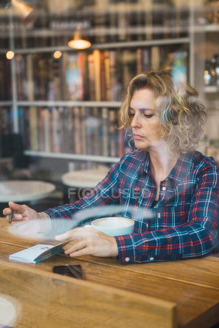 Donna seduta nel caffè e che scrive nel taccuino — Foto stock