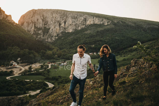 Junger Mann und Frau gehen einen steinigen Hügel hinunter, während sie gemeinsam Zeit in der Natur verbringen — Stockfoto