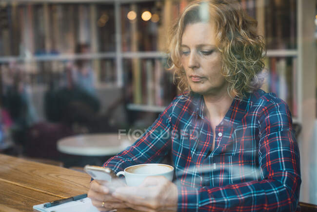 Femme assise dans un café avec une tasse de café — Photo de stock