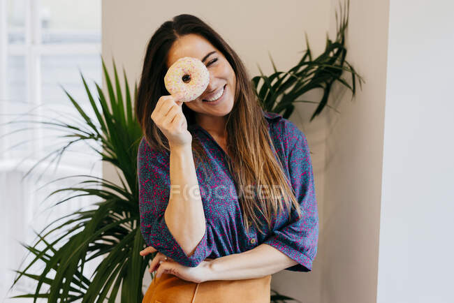 Cheerful woman looking through donut — Stock Photo