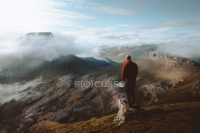 Escursionista in piedi sul bordo della montagna e guardando la vista sulle isole Feroe — Foto stock