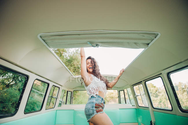 Cheerful young woman dancing inside retro van — Stock Photo
