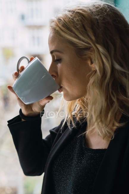 Nahaufnahme einer blonden jungen Frau, die Kaffee trinkt — Stockfoto
