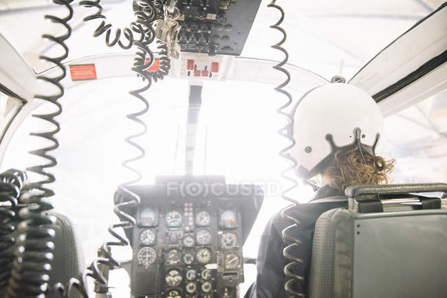 Female pilot in helmet sitting and operating in helicopter — Stock Photo