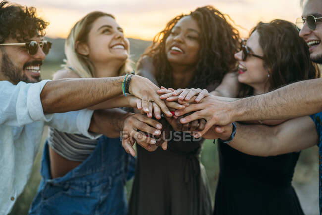 Grupo de jóvenes de la cosecha sonriendo y tomados de la mano mientras pasan tiempo en la naturaleza - foto de stock