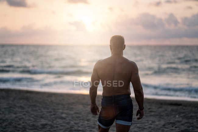Strong old man posing on beach — Stock Photo