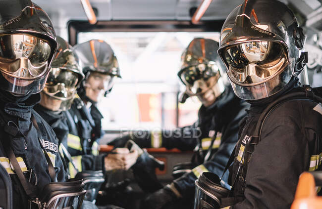 Vigili del fuoco irriconoscibili con casco in un veicolo di emergenza — Foto stock