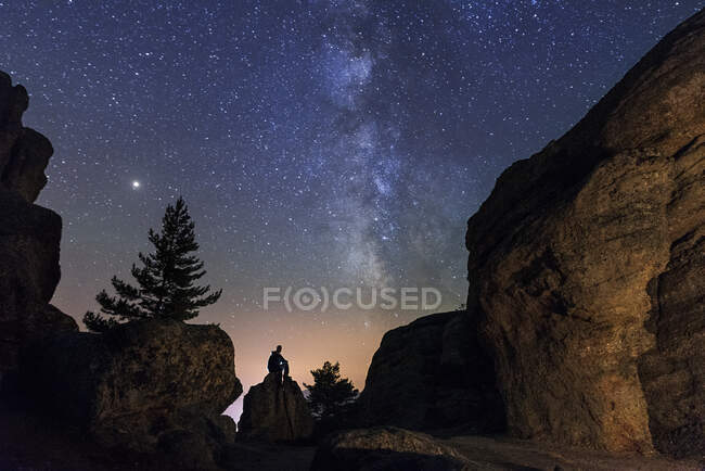 Uomo seduto sotto le stelle Via Lattea nella roccia silhouette montagne. Soria, Spagna — Foto stock