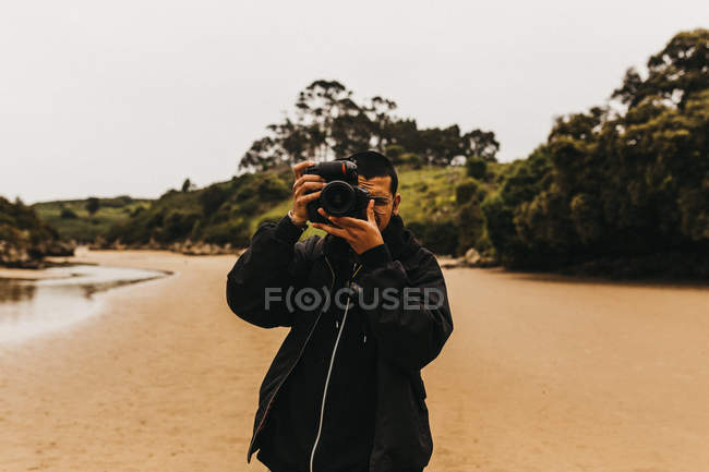 Hombre tomando fotos del océano - foto de stock