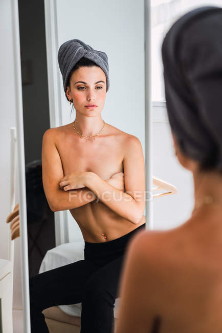 Молодий топлес жінку, що стоїть перед дзеркалом з рушником на голову — стокове фото
