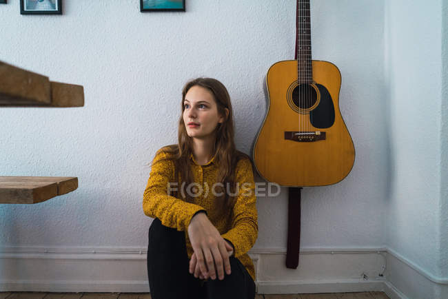 Mujer sentada cerca de guitarra - foto de stock