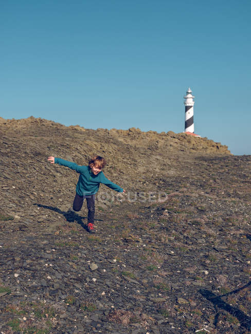 Веселый мальчик бежит на маяк — стоковое фото