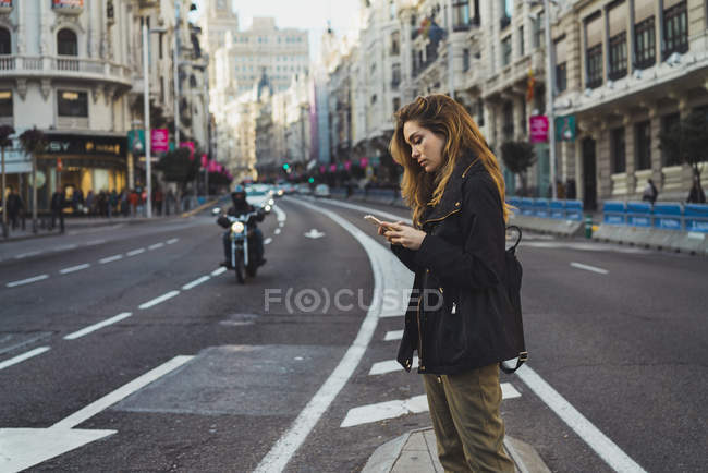 Mulher usando smartphone na estrada na cidade — Fotografia de Stock