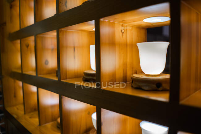 White traditional ceramic cups for tea ceremony placed in wooden shelf — Stock Photo