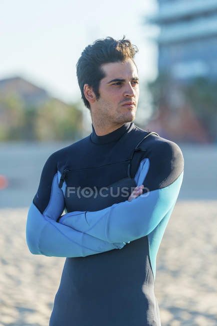 Young man wearing neoprene and standing in the beach — Stock Photo