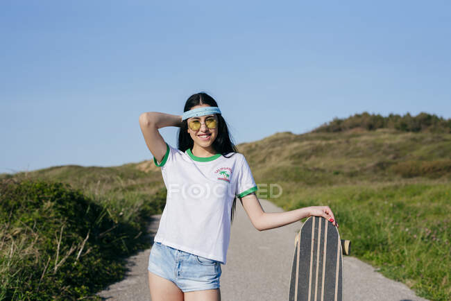 Stilvolles Teenie-Mädchen mit langem Brett im Sommer — Stockfoto