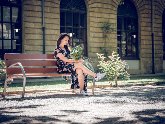 Donna sognante con mazzo di fiori sulla panchina — Foto stock