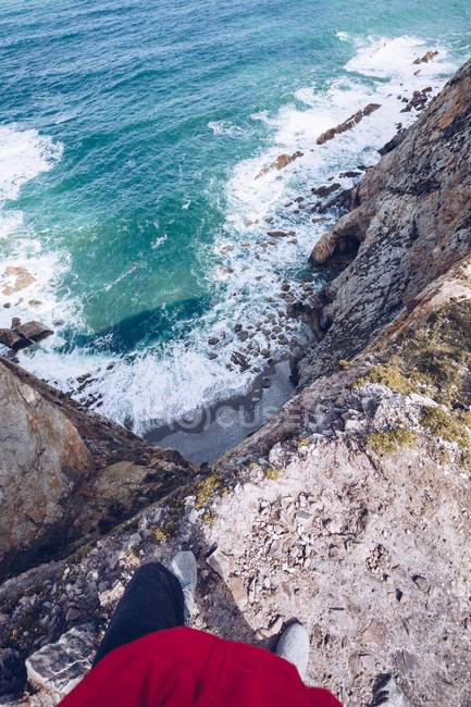 Image recadrée d'une personne debout sur une falaise pierreuse au-dessus d'une belle mer éclaboussante dans les Asturies, Espagne — Photo de stock
