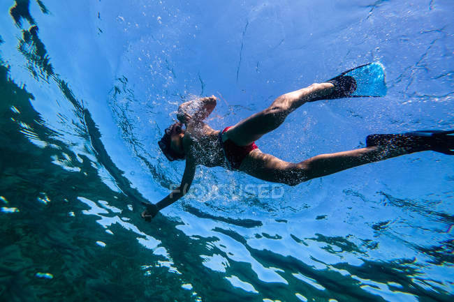 Boy in diving mask and flippers snorkeling in blue water of sea — Stock Photo