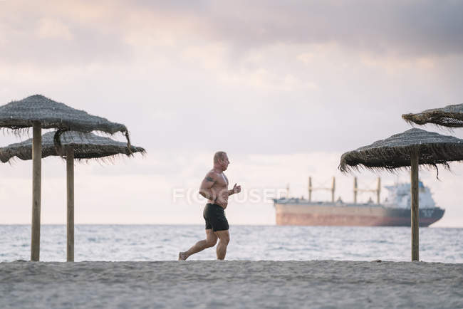 Homem velho forte faz exercício na praia — Fotografia de Stock