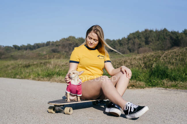 Girl with dog on long board in nature — Stock Photo