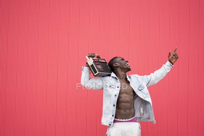 Африканский мужчина позирует с винтажным радиоприбором на красном фоне — стоковое фото