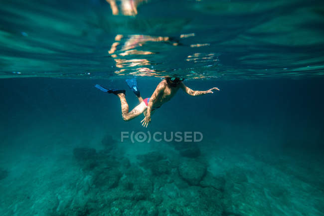 Неузнаваемый мальчик плавает с маской в морской воде — стоковое фото