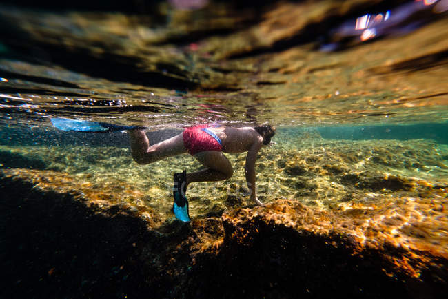 Menino irreconhecível mergulho no mar sobre a rocha — Fotografia de Stock