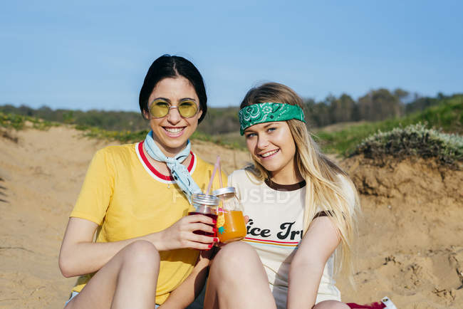 Модні дівчата з напоями на пляжі — стокове фото