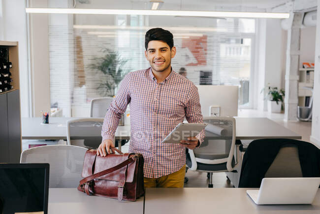 Hombre sonriente con tableta en la oficina - foto de stock