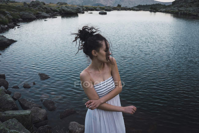 Giovane donna in abito in piedi vicino lago increspatura — Foto stock