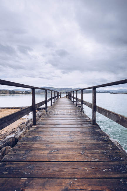 Weathered umber pier located on shore near surface of calm water on cloudy day in Asturias, Spain — Stock Photo