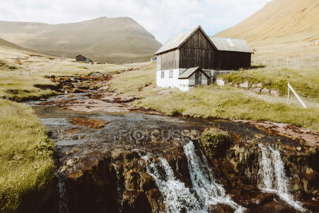 Водоспад і дерев'яні сільський будинок на схилі на Feroe острови — стокове фото