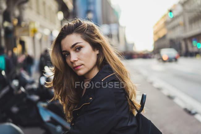 Young woman leaning standing in city and looking at camera — Stock Photo
