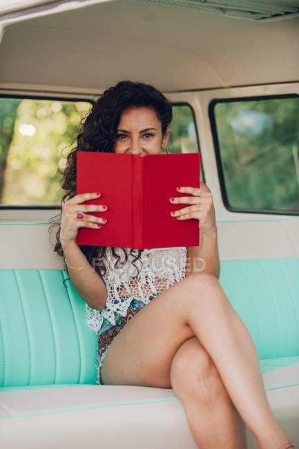 Retrato de mulher sentada dentro da caravana retro e livro segurando — Fotografia de Stock