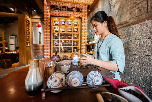 Joven mujer asiática haciendo preparaciones y elaborando té oriental - foto de stock