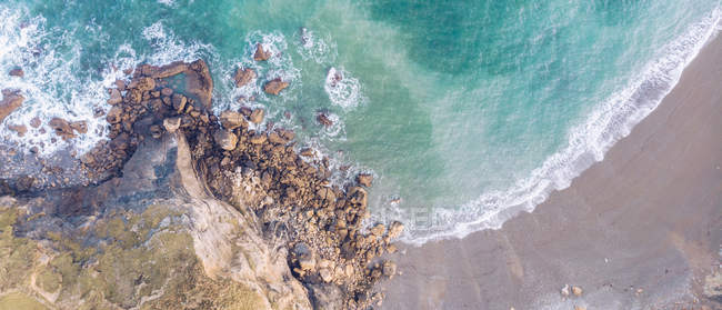Vue imprenable sur les éclaboussures d'eau de mer près de longues falaises rocheuses par temps nuageux dans les Asturies, Espagne — Photo de stock