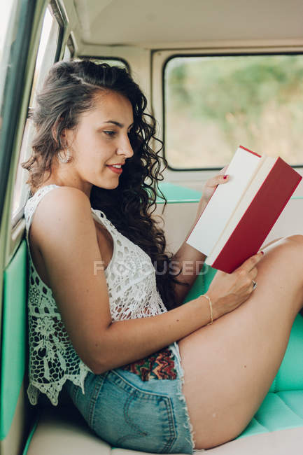 Жінка сидить всередині каравана і читає книгу — стокове фото
