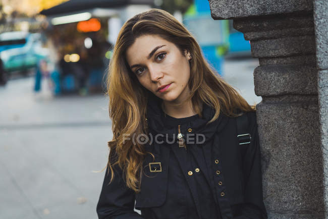 Porträt einer jungen Frau lehnt an Säule auf der Straße — Stockfoto