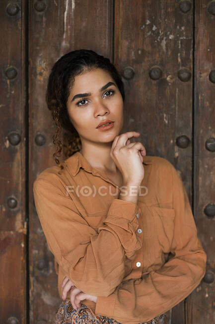 Beautiful African-American charming young lady in light brown cloths with crossing hands looking at camera — Stock Photo