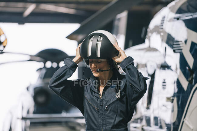 Пілот дівчина позує зі своїм гелікоптером і шоломом — стокове фото