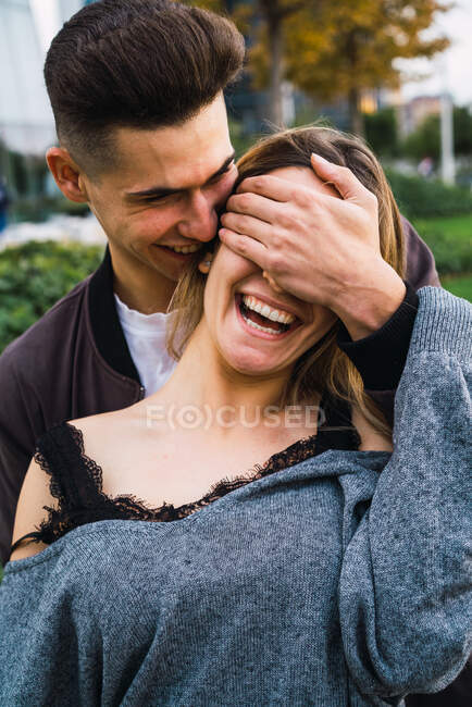 Jovem alegre cobrindo os olhos de gargalhadas namoradas enquanto posam felizes juntos. — Fotografia de Stock